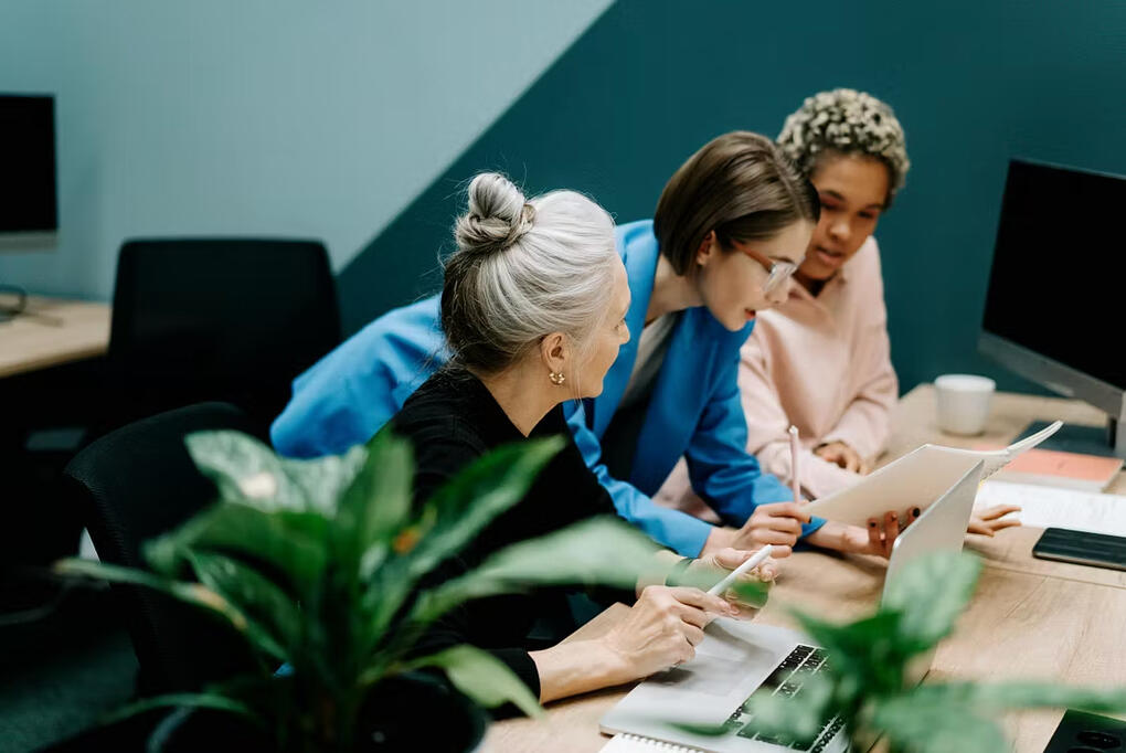 The Gal Project - Bold Visions for 2026 Feature Three women collaborating at a conference table, reviewing notes and a laptop in a modern workspace.